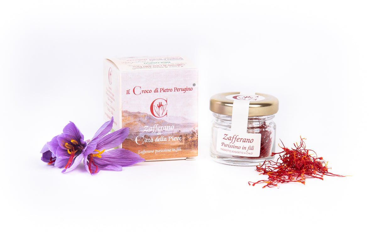 Barattolo di zafferano in fili con la confezione, un fiore di croco e alcuni fili