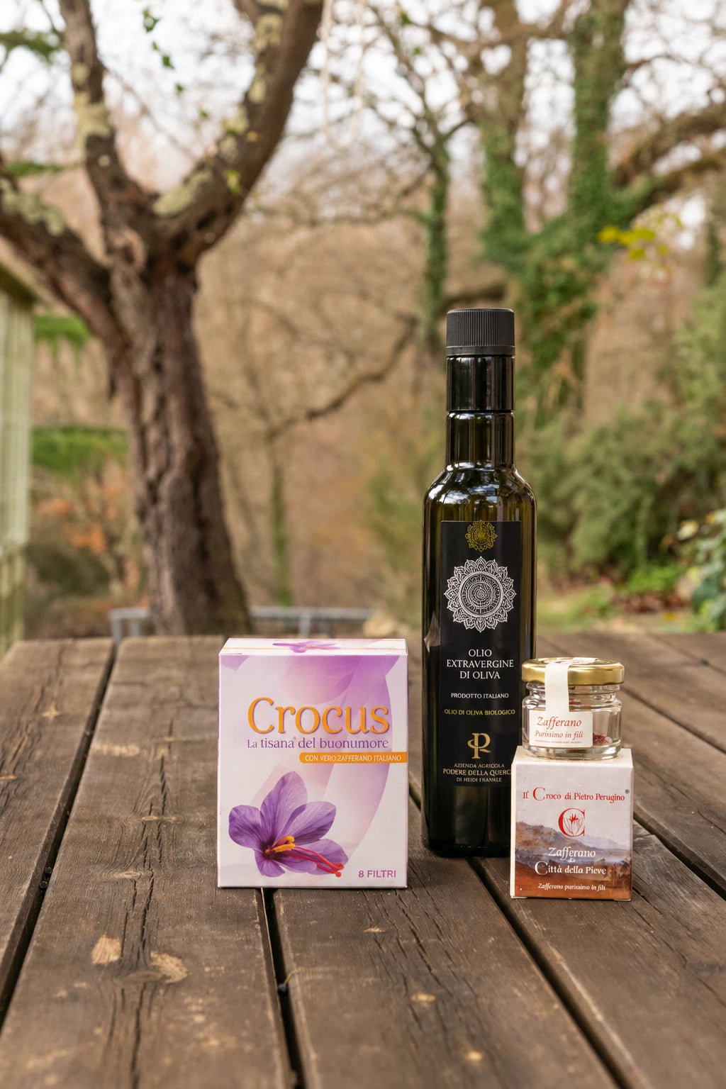 Box Assaggio del Podere: olio extravergine, zafferano in fili e tisana Crocus su un tavolo di legno